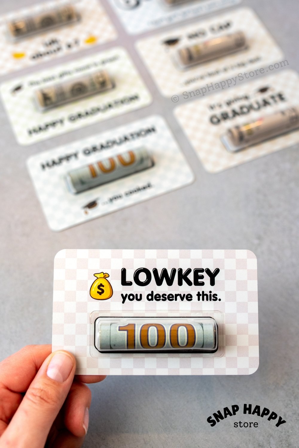 Graduation card with 'LOWKEY you deserve this' text, held by a hand.